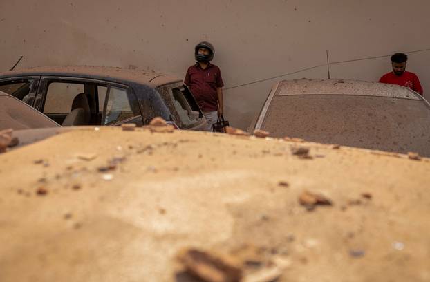 People stand next to damaged vehicles in a neighbourhood, following Pakistan's military operation against India, in Rehari, Jammu