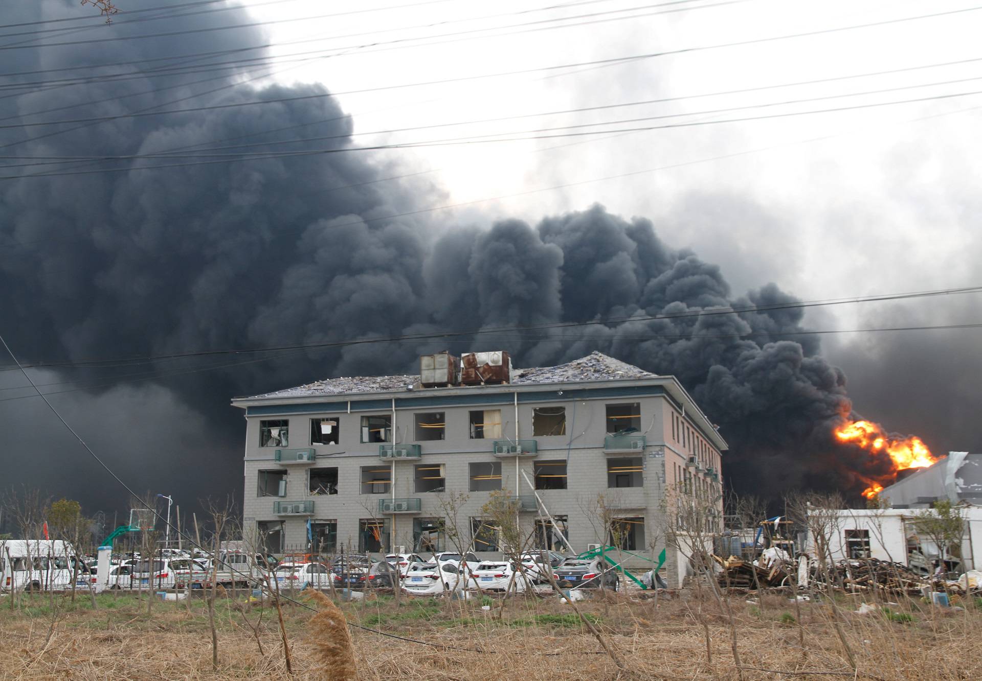 Smoke billows from fire behind a damaged building following an explosion at the pesticide plant owned by Tianjiayi Chemical, in Xiangshui