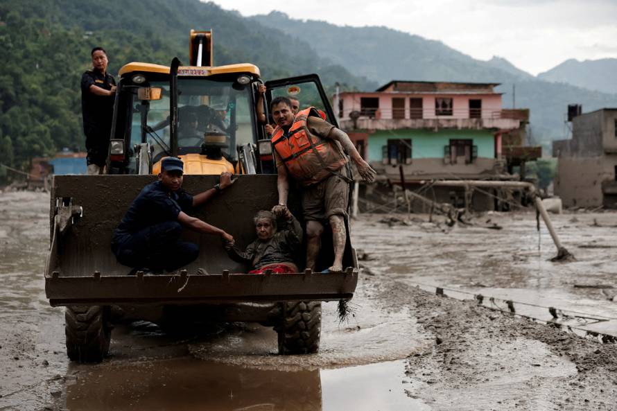 A survivor is transported to a safer place in heavy machinery following a flash flood at Trishuli, Nepal
