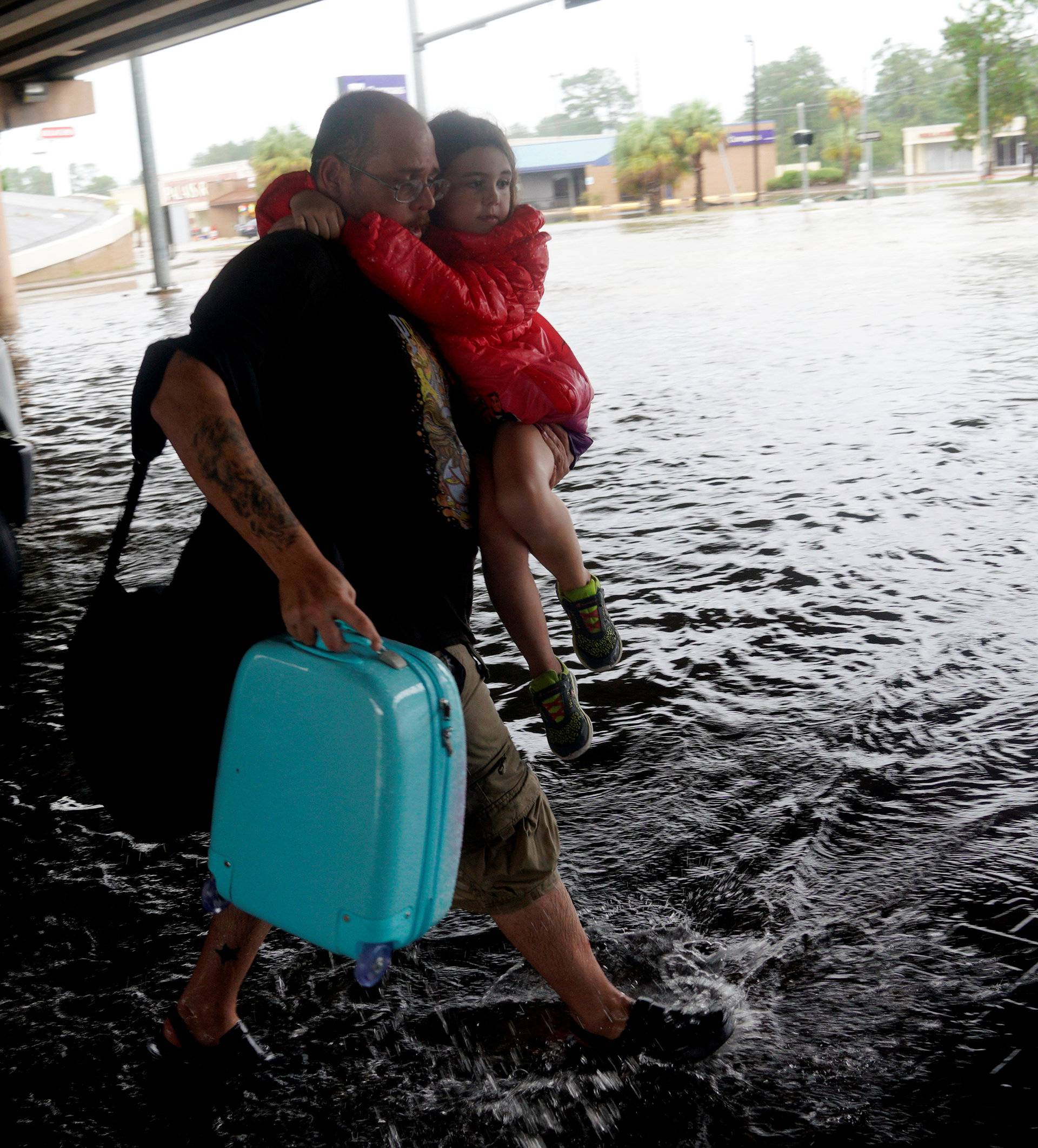 A man carries a child after being evacuated by dump truck from the Hurricane Harvey floodwaters in Dickinson