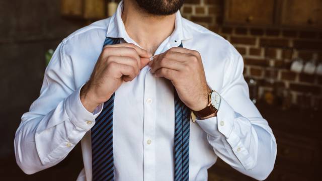 businessman fastening buttons on shirt