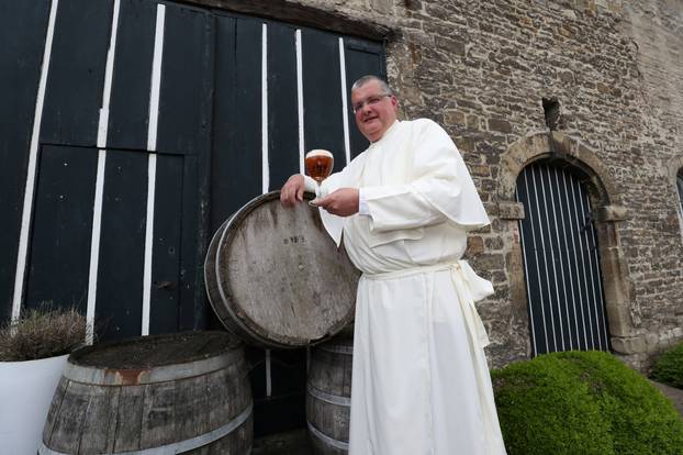 Norbertine Father Karel poses with a Grimbergen beer, symbolised by a phoenix, in the courtyard of the Belgian Abbey of Grimbergen before announcing that the monks will return to brewing after a break of two centuries, in Grimbergen