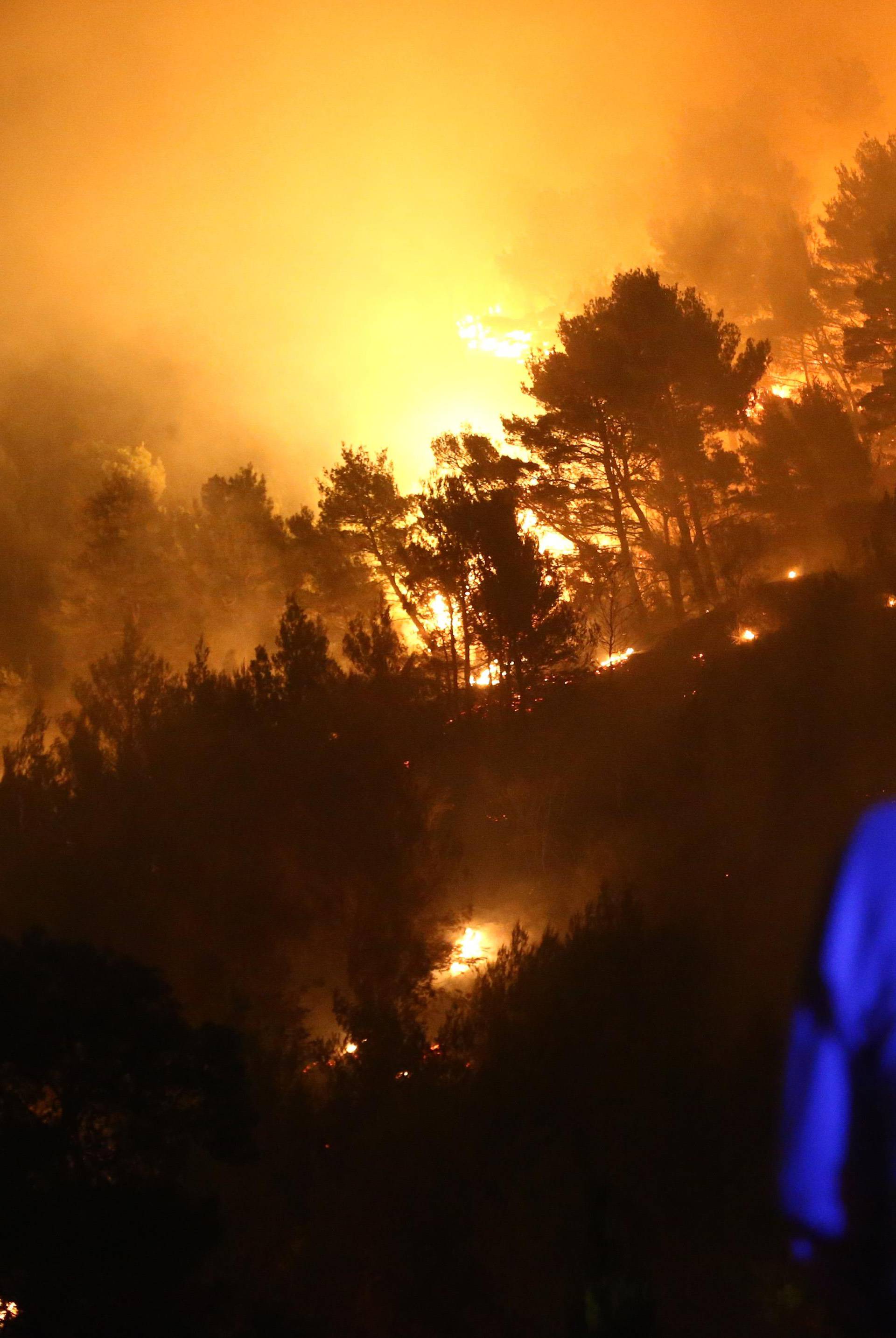 A man observes wildfire in the village of Mravince near Split