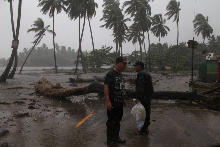 Men stand in the rain as Hurricane Irma moves off from the northern coast of the Dominican Republic, in Nagua
