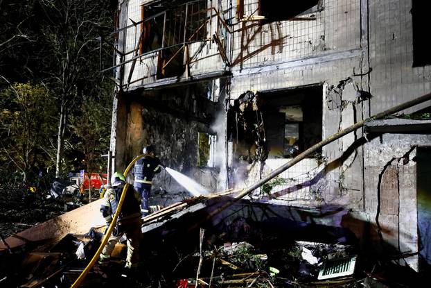 Firefighters work at the site of an apartment building hit by a Russian missile strike in Kyiv