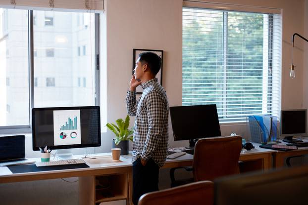 A wide shot of a businessman in an empty office on a phonecall