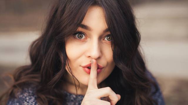 Portrait of beautiful woman with finger on lips.