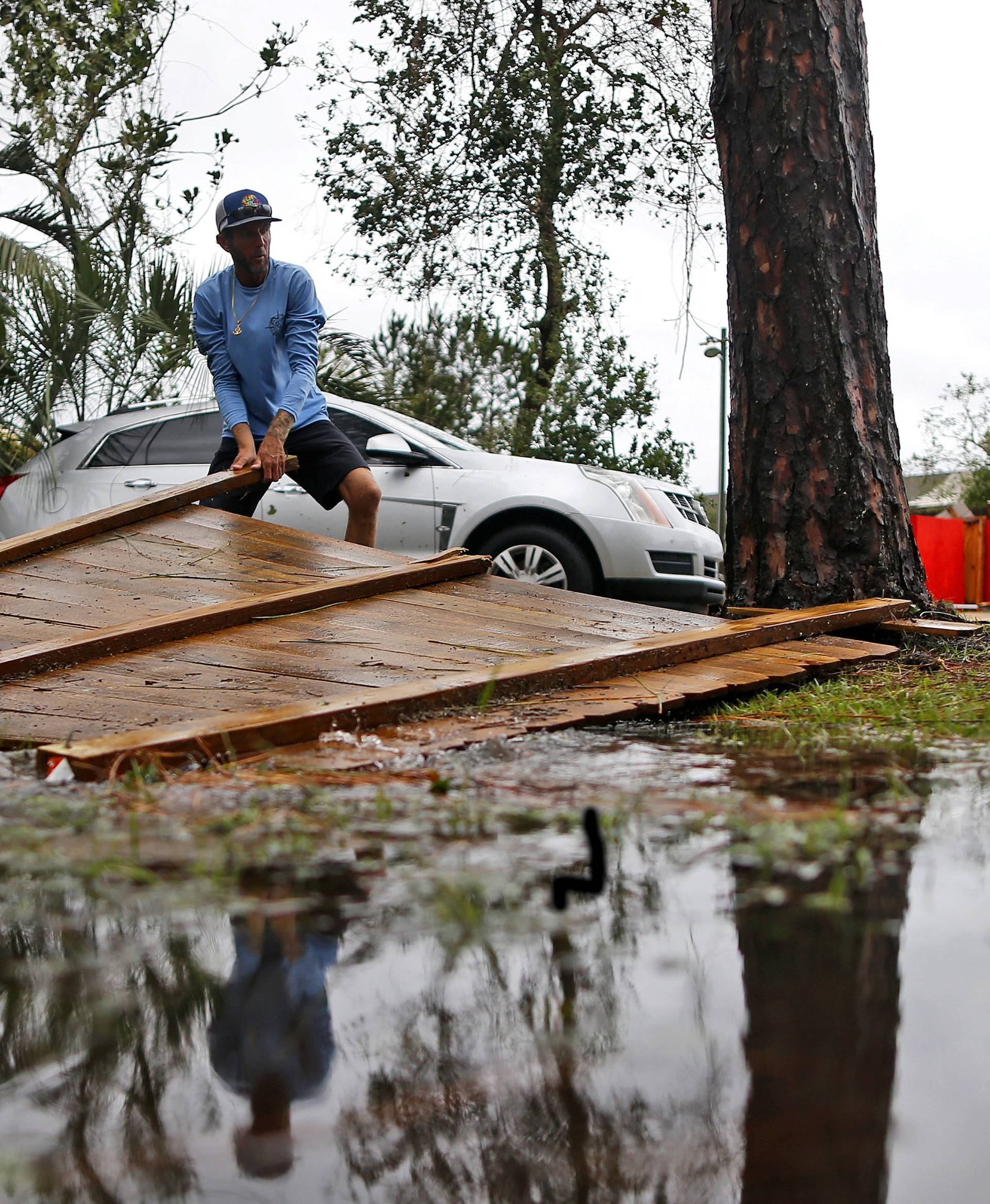 Joseph Howat clears a damaged fence by Hurricane Michael at his business in Panama City Beach