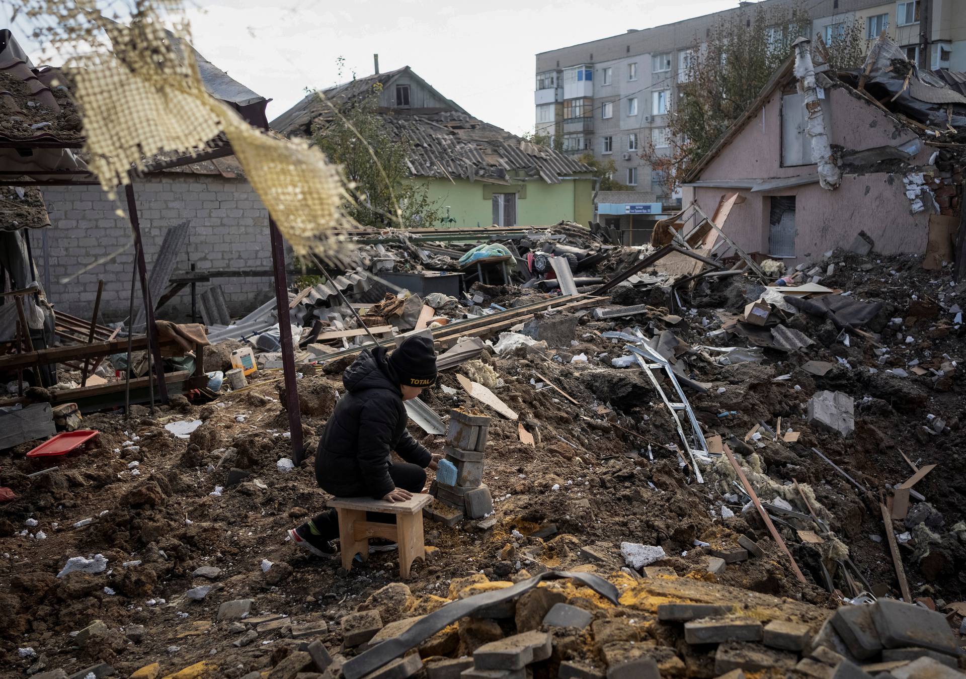 A boy plays on ruins of his grandmother's house, in Kupiansk