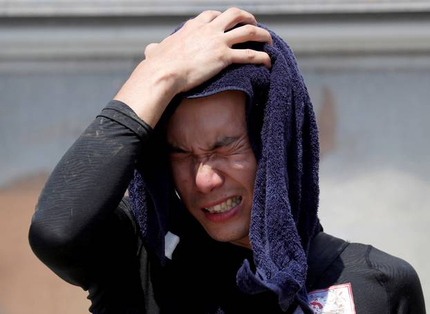 FILE PHOTO: A volunteer, for recovery work, wipes his sweat as he takes a break in a heat wave at a flood affected area in Kurashiki