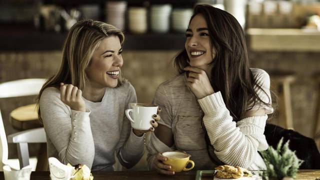Two cheerful women having fun during coffee time in a cafe.