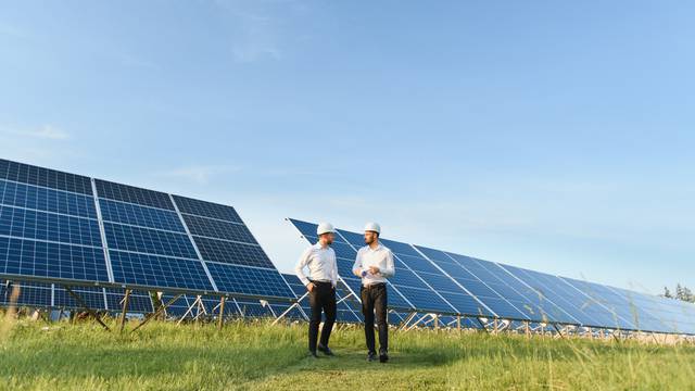 The,Solar,Farm(solar,Panel),With,Two,Engineers,Walk,To,Check