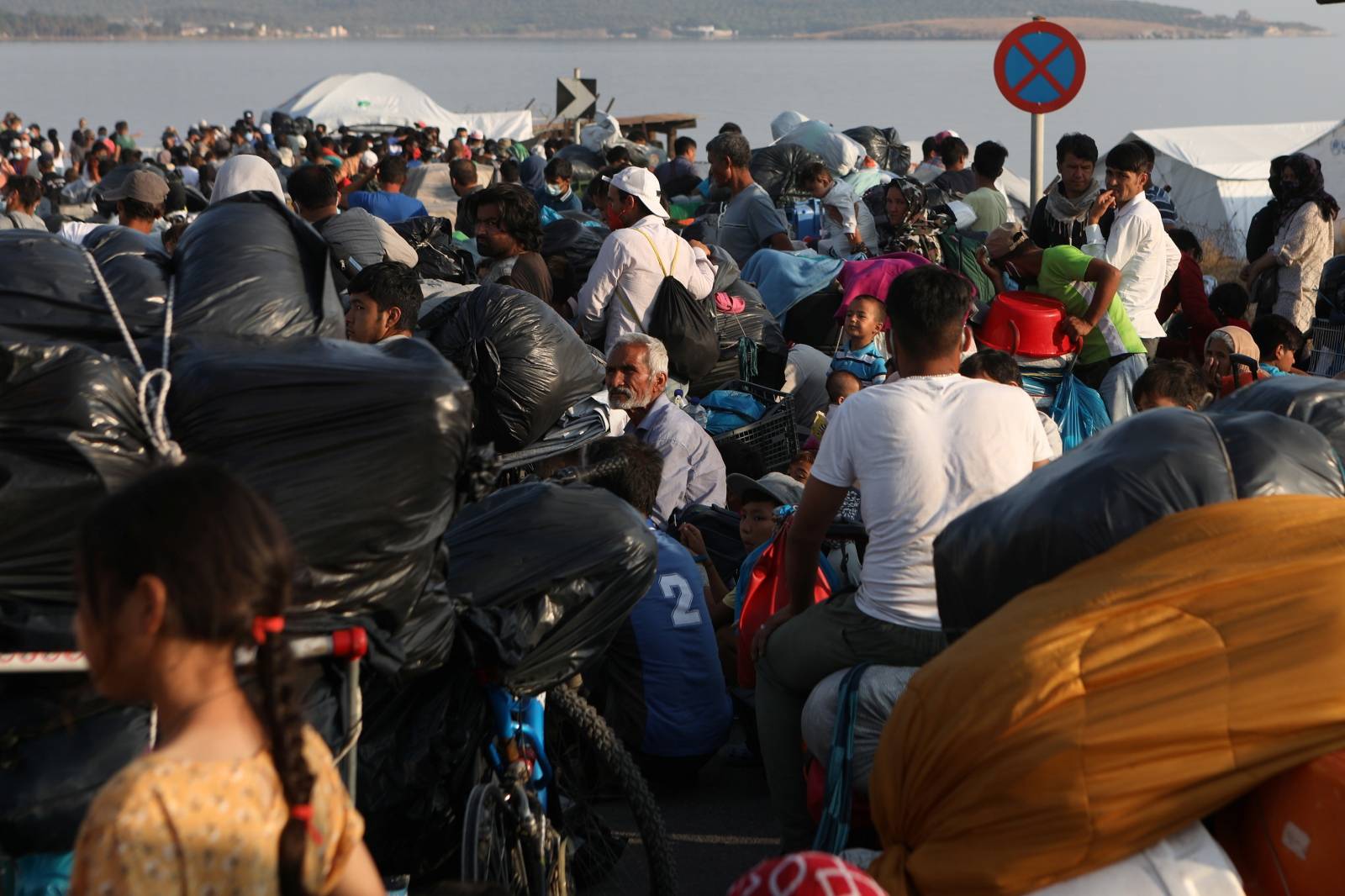 Refugees and migrants, from the destroyed Moria camp, line up to enter a new temporary camp, on the island of Lesbos