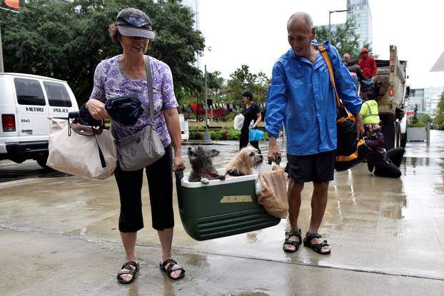 A couple of evacuees carry their dogs into the the George R. Brown Convention Center after Hurricane Harvey inundated the Texas Gulf coast with rain causing widespread flooding