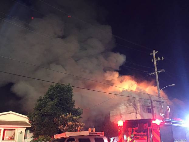 Flames rise from the top of a warehouse, which caught fire during a dance party in Oakland