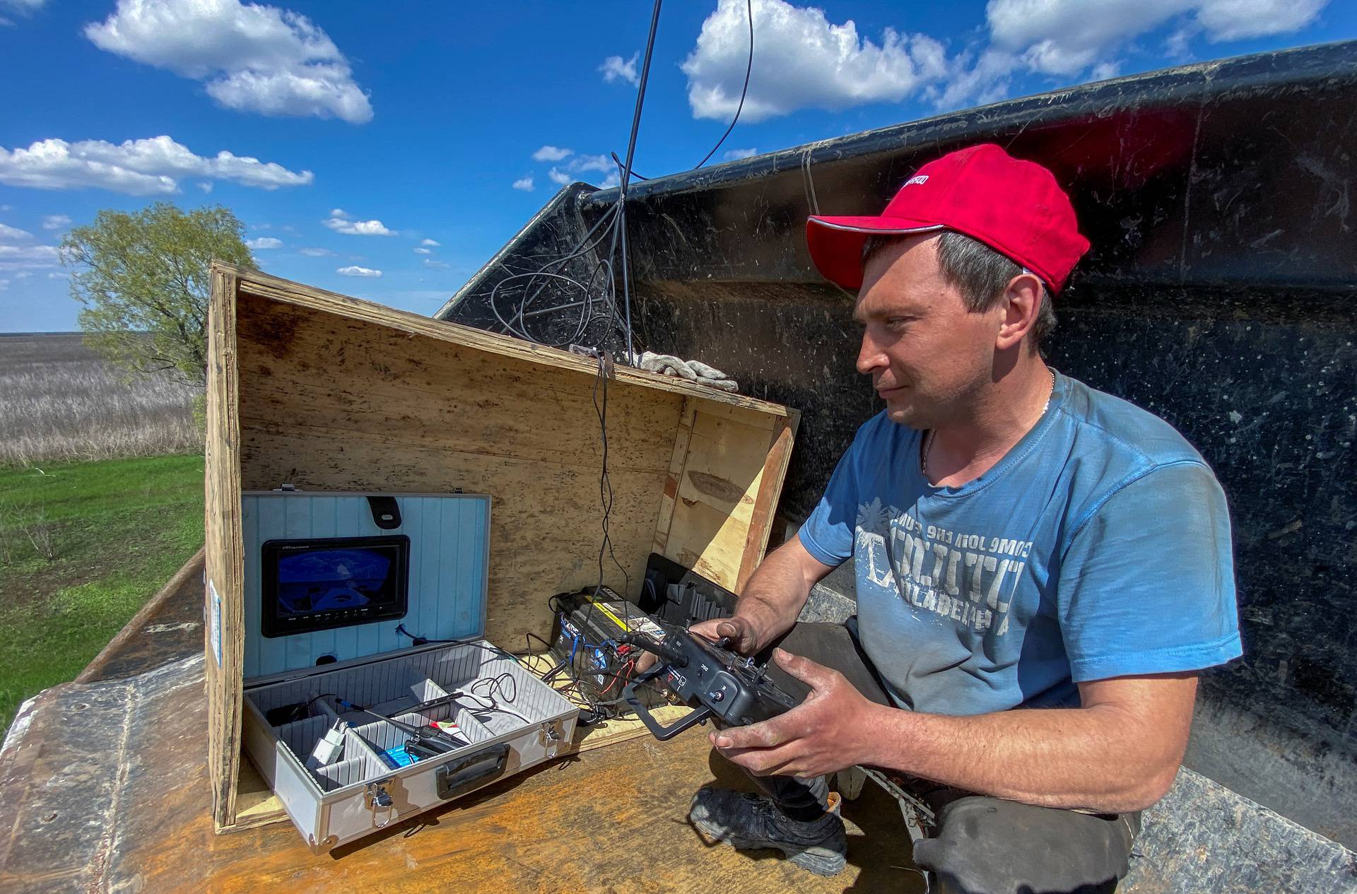 Worker uses a remote control to operate a demining machine made of tractor and armoured plates from destroyed Russian military vehicles in a field near the village of Hrakove