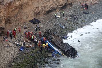 Rescue workers work at the scene after a bus crashed with a truck and careened off a cliff along a sharply curving highway north of Lima