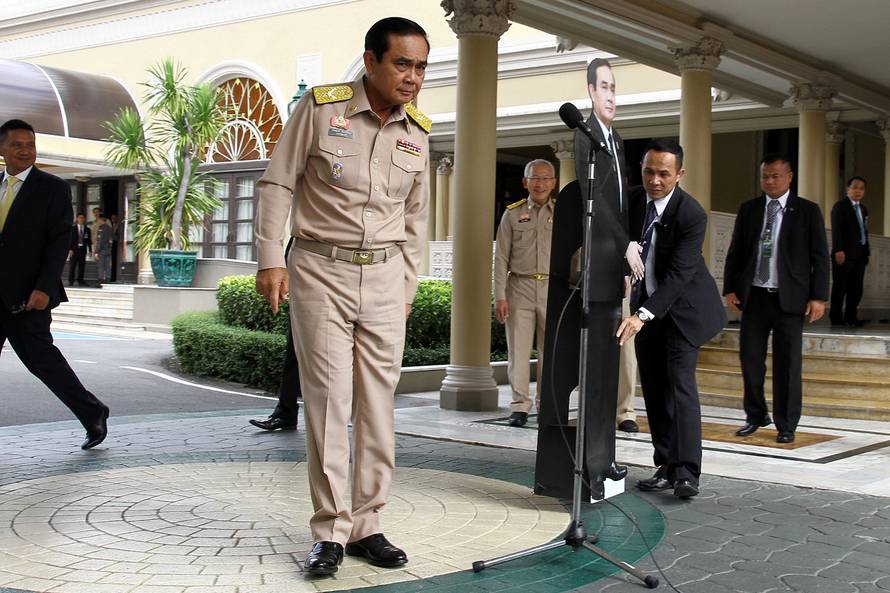 Thailand's Prime Minster Prayuth Chan-ocha speaks to reporters next to a cardboard cut-out of himself at the government house in Bangkok