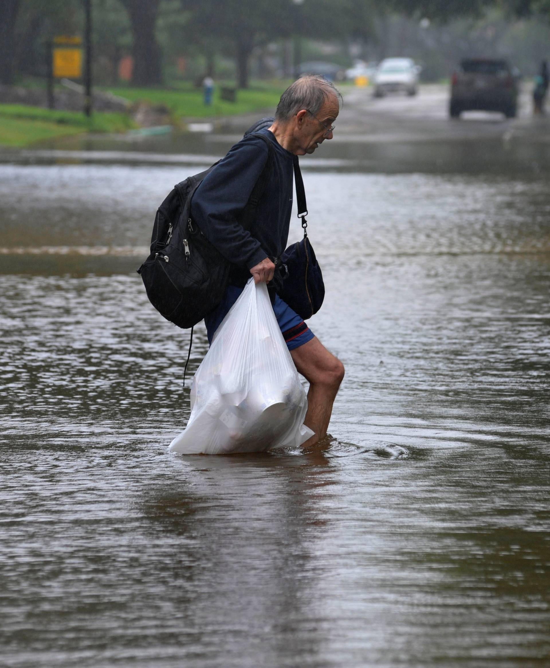 A man carries his belongings through flood waters after Hurricane Harvey inundated the Texas Gulf coast with rain causing widespread flooding