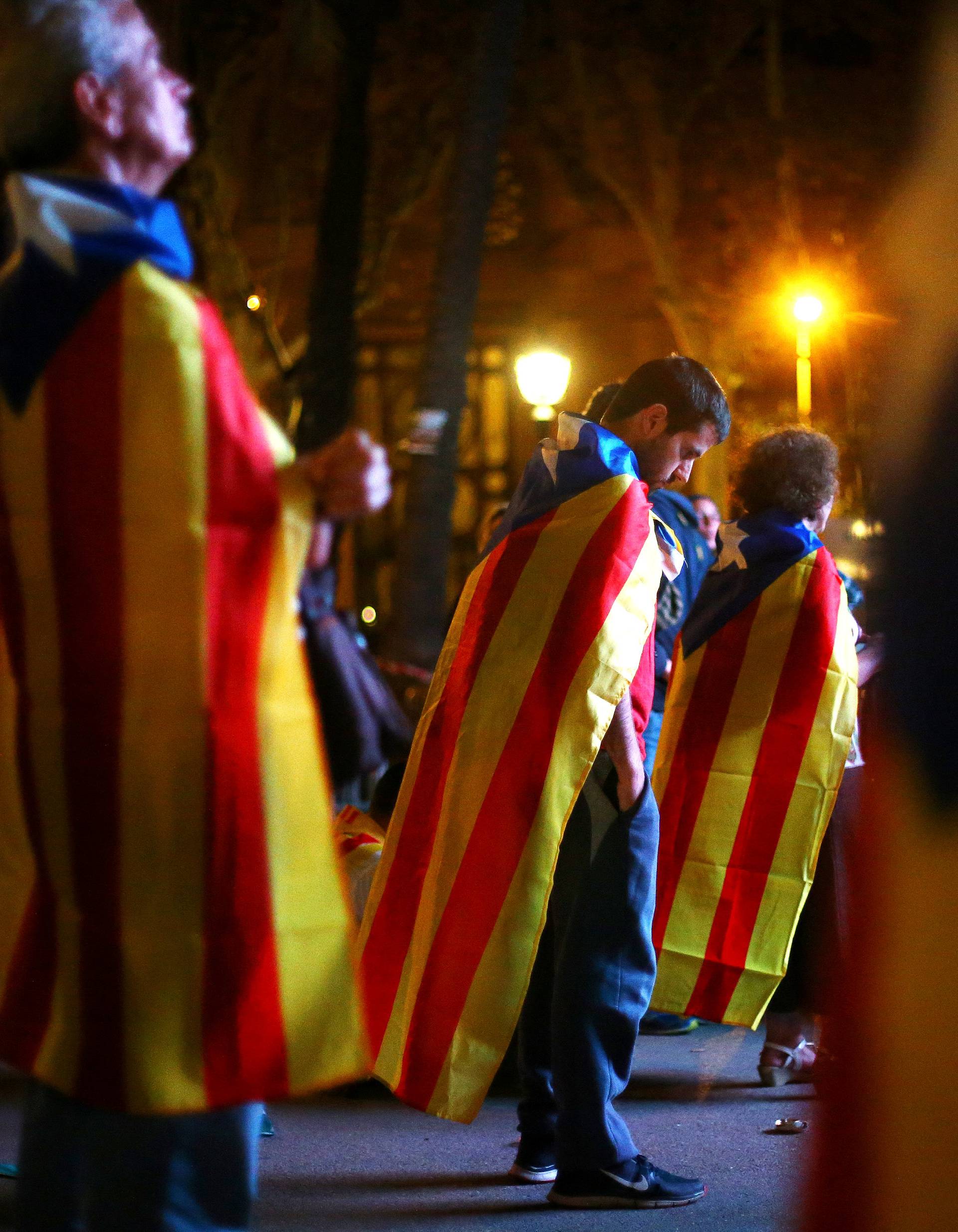 People react as they watch a session of the Catalonian regional parliament on a giant screen at a pro-independence rally in Barcelona