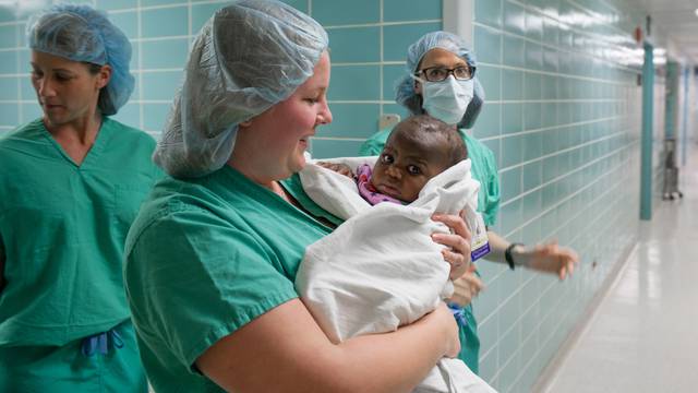 Hospital staff carry 10-month old "Baby Dominique" into surgery to treat the infant born with four legs and two spines at Advocate Children's Hospital in Park Ridge, Illinois