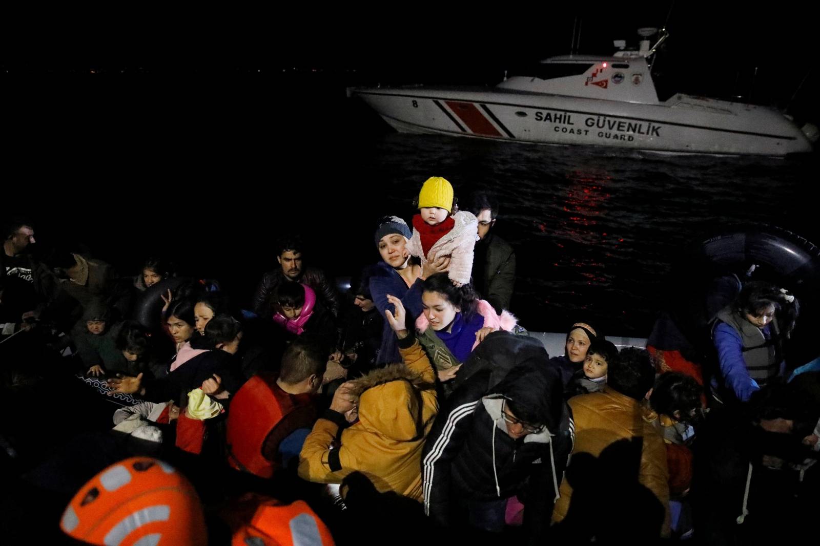 Migrants board a Turkish coast guard boat following a failed attempt to cross to the Greek island of Lesbos, on the waters of the North Aegean Sea, off the shores of Canakkale
