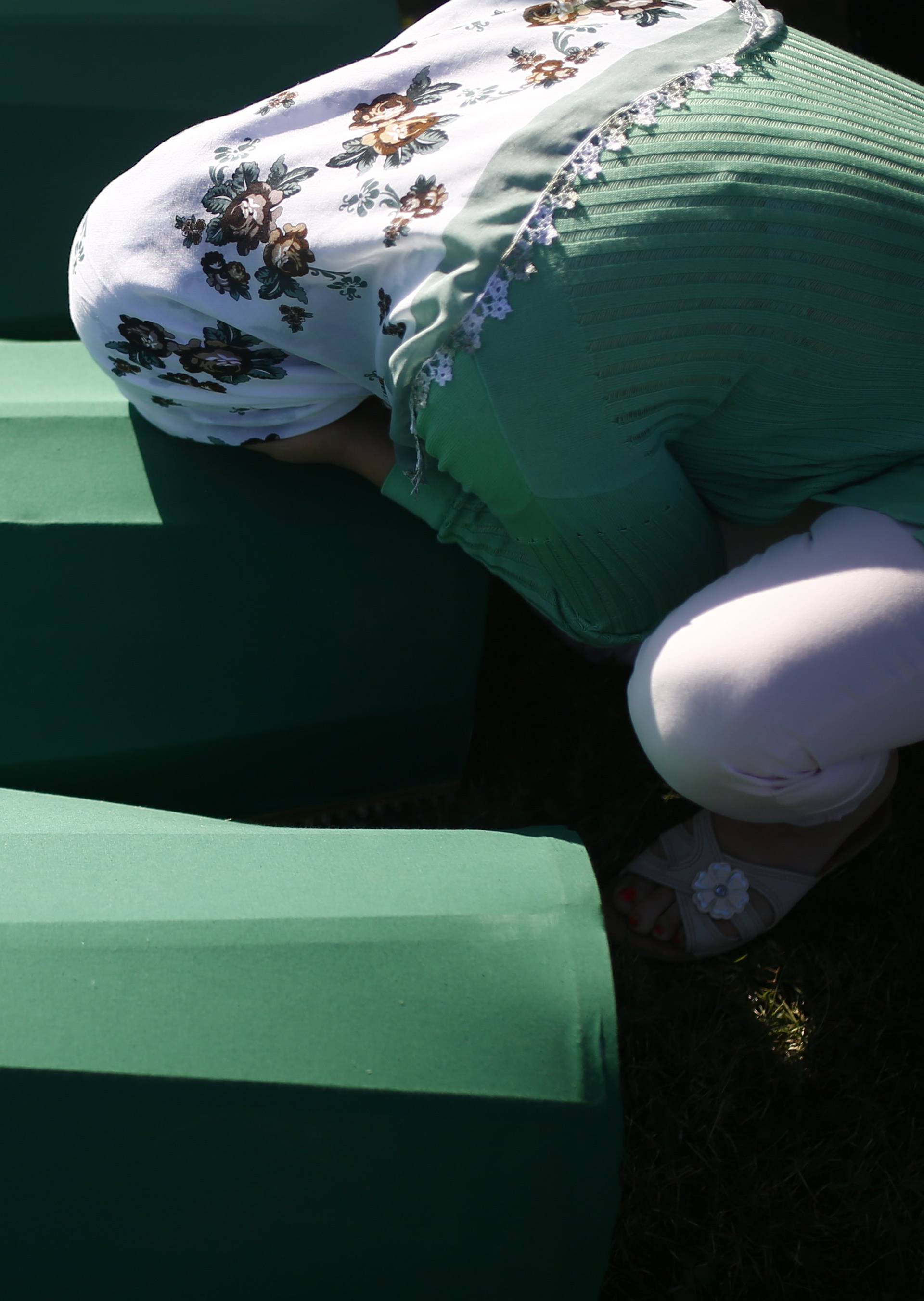 A woman mourns near coffins of her relatives, who are newly identified victims of the 1995 Srebrenica massacre, which are lined up for a joint burial in Potocari near Srebrenica