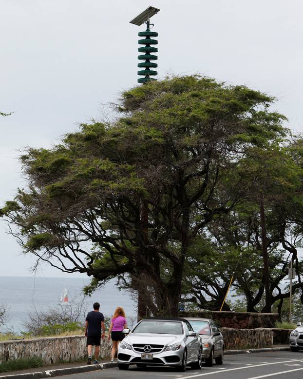 People walk by a tsunami warning tower near Diamond Head Lookout in Honolulu