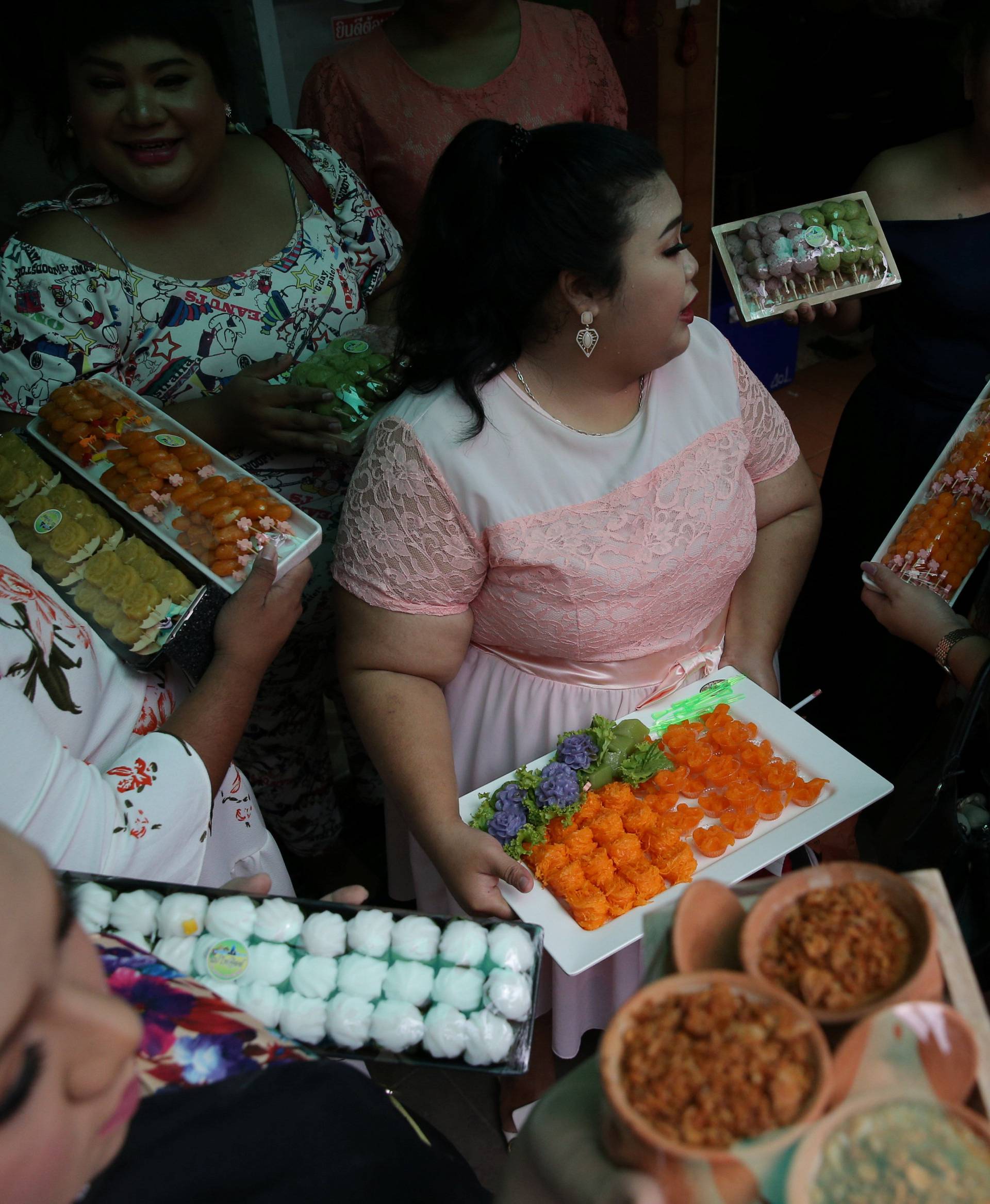 Participants in the Miss Jumbo beauty contest hold up desserts at a dessert shop in Nakhon Ratchasima