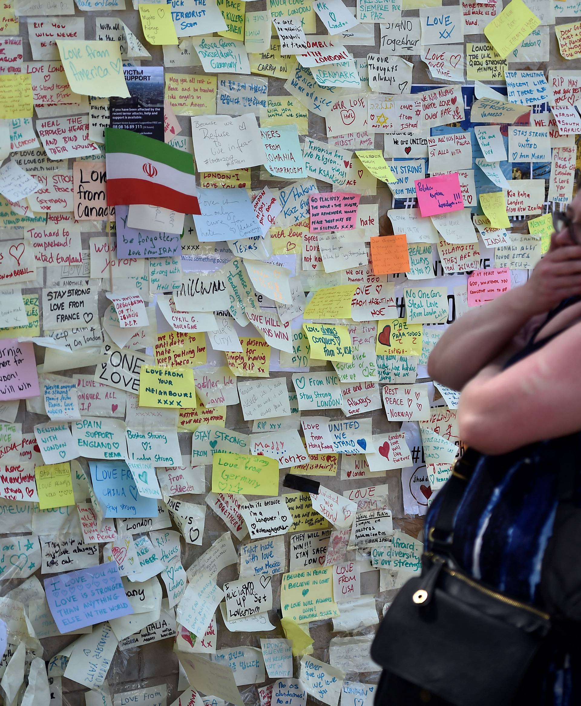 A woman reacts in front of a wall of messages in Borough Market, which officially re-opened today following the recent attack, in central London