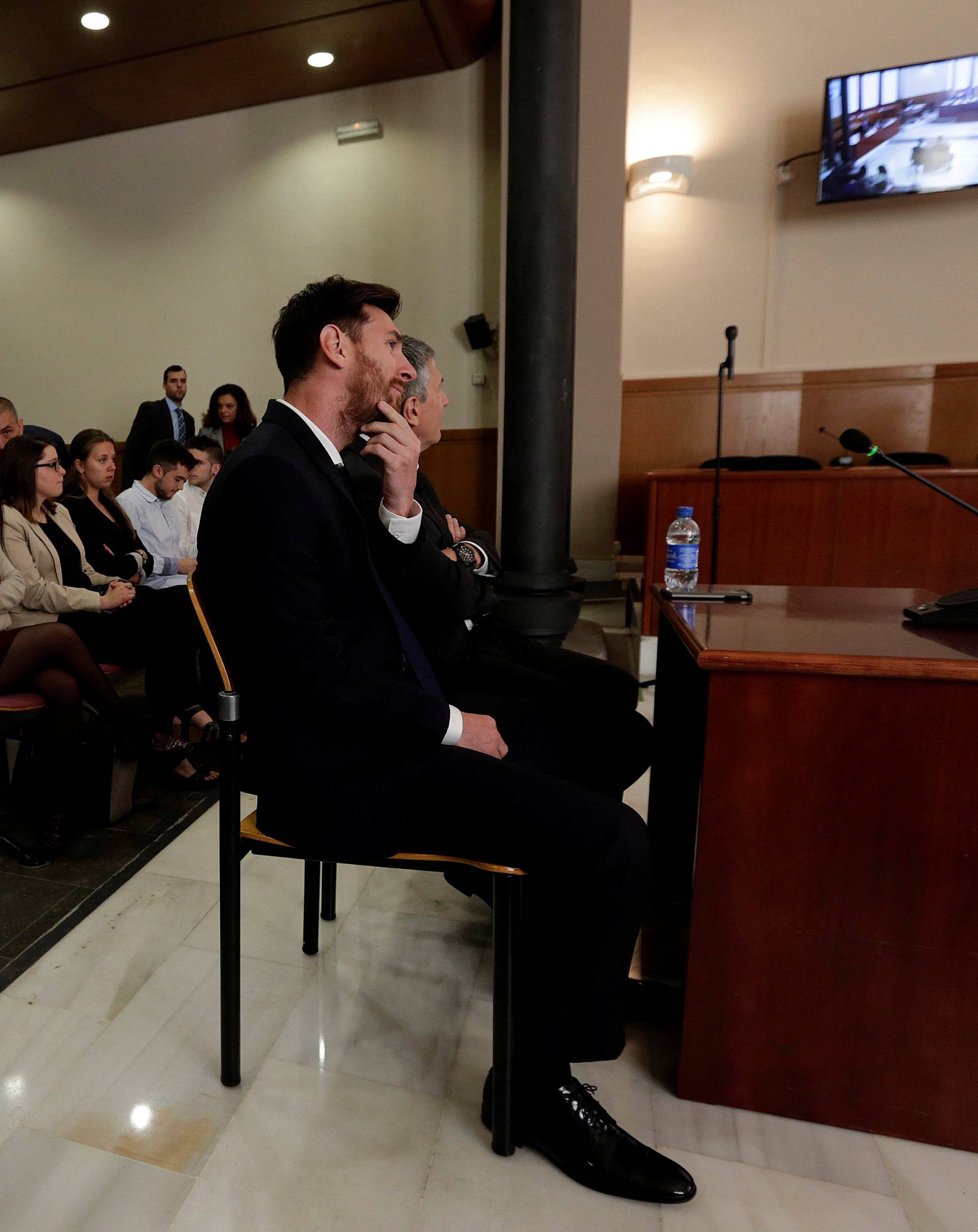 Barcelona's Argentine soccer player Lionel Messi sits in court with his father Jorge Horacio Messi during their  trial for tax fraud in Barcelona