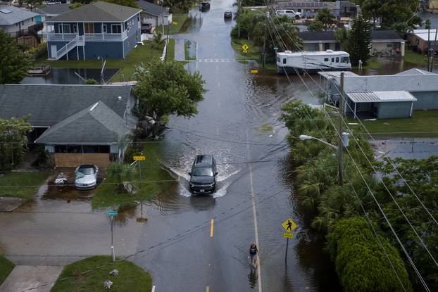Resident walk down flooded street after Hurricane Idalia in Hudson, Florida