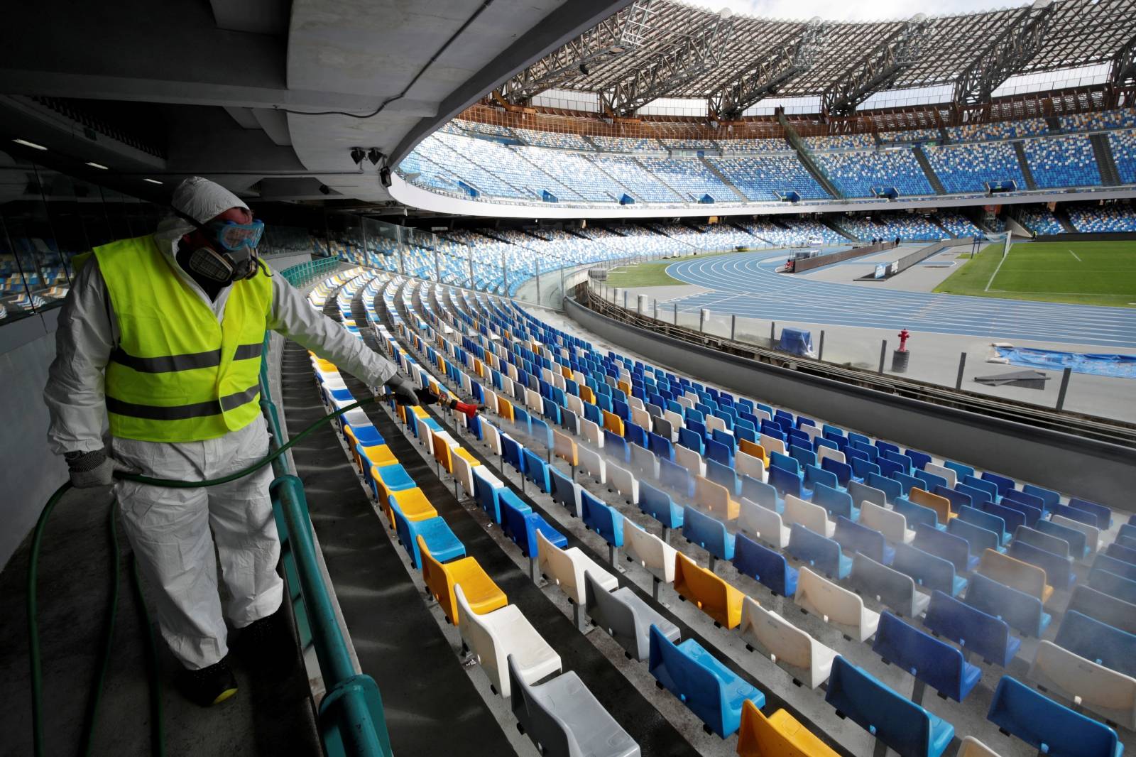 FILE PHOTO: A cleaner wearing a protective suit sanitises seats at the San Paolo stadium ahead of the second leg of the Coppa Italia semi-final between Napoli and Inter Milan, which has since been postponed