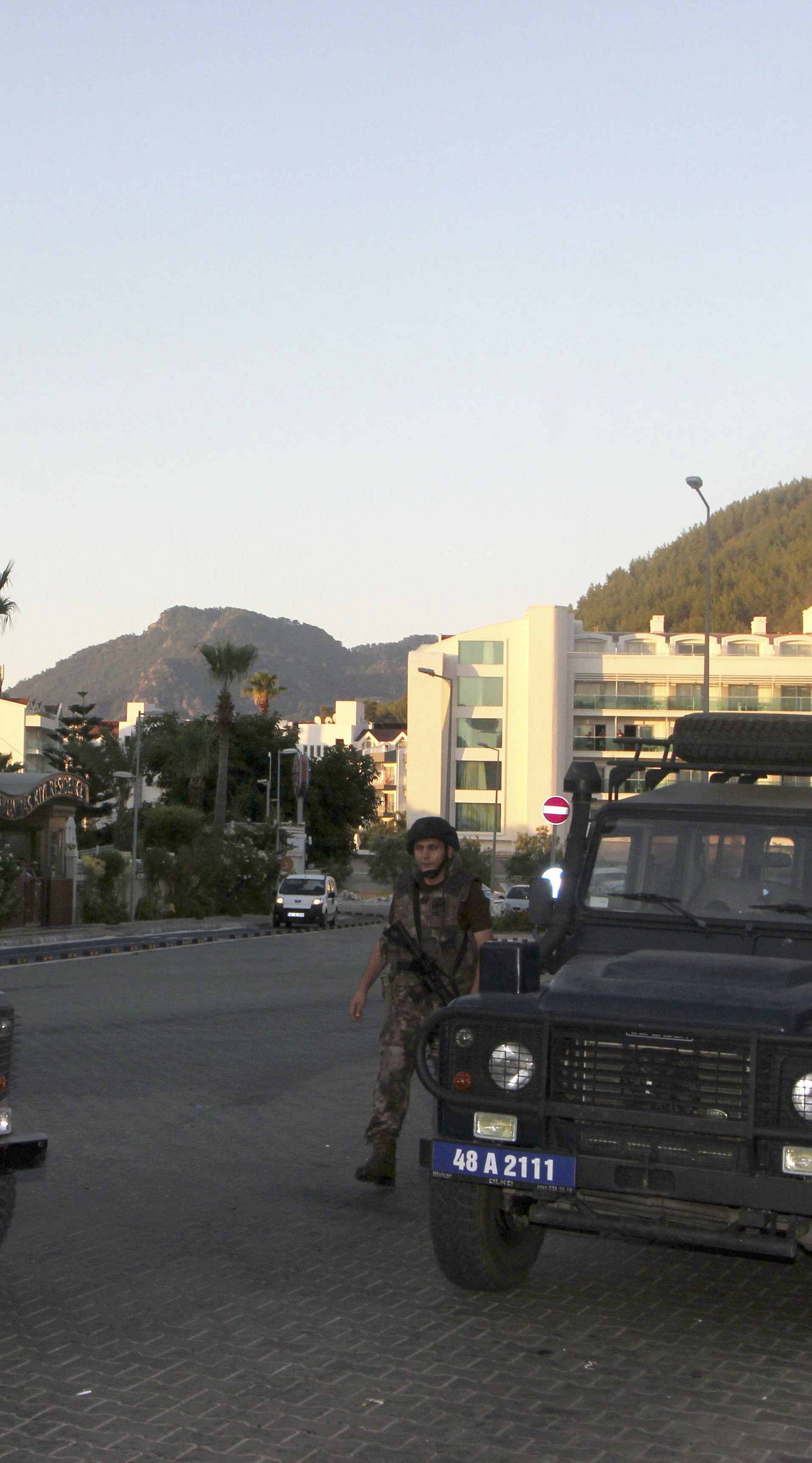 Policemen patrol the streets as two police vehicles block a road in the resort town of Marmaris