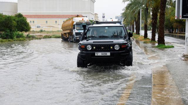 Cars drive through a flooded road following a rainstorm in Dubai
