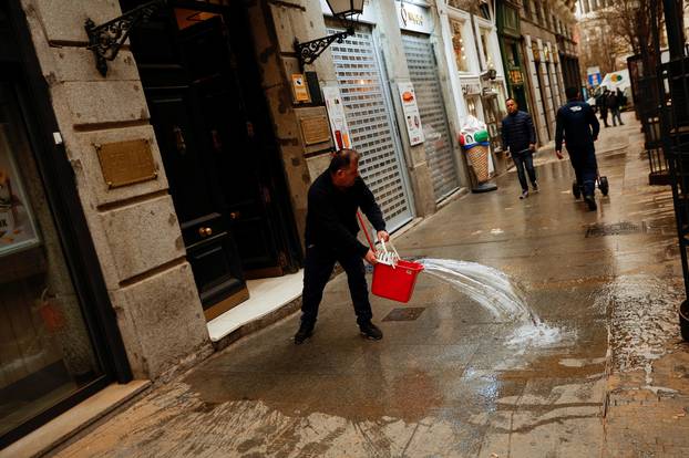 A man cleans the sidewalk as storm Celia blew sand from the Sahara desert over Madrid