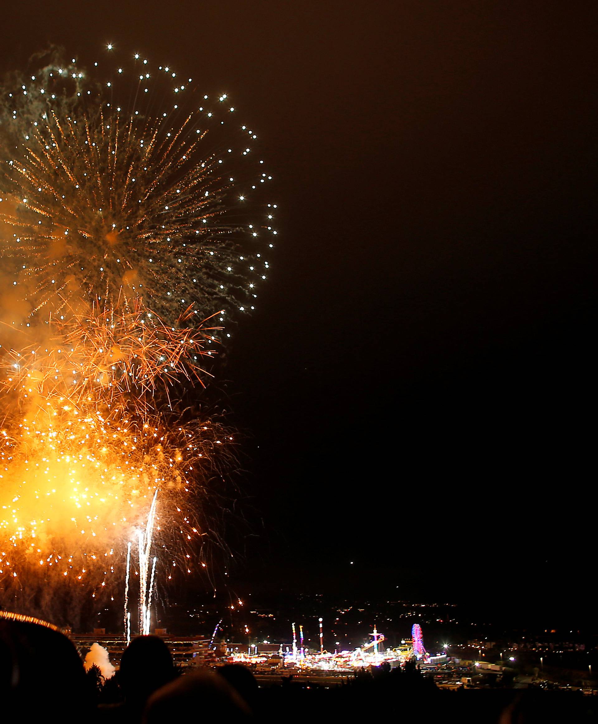 Children sit on top of a car to watch 4th of July fireworks above the San Diego County Fair as Independence Day is celebrated in Solana Beach, California