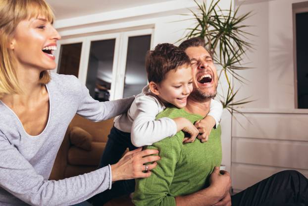 Happy family having fun on floor of in living room at home, laug