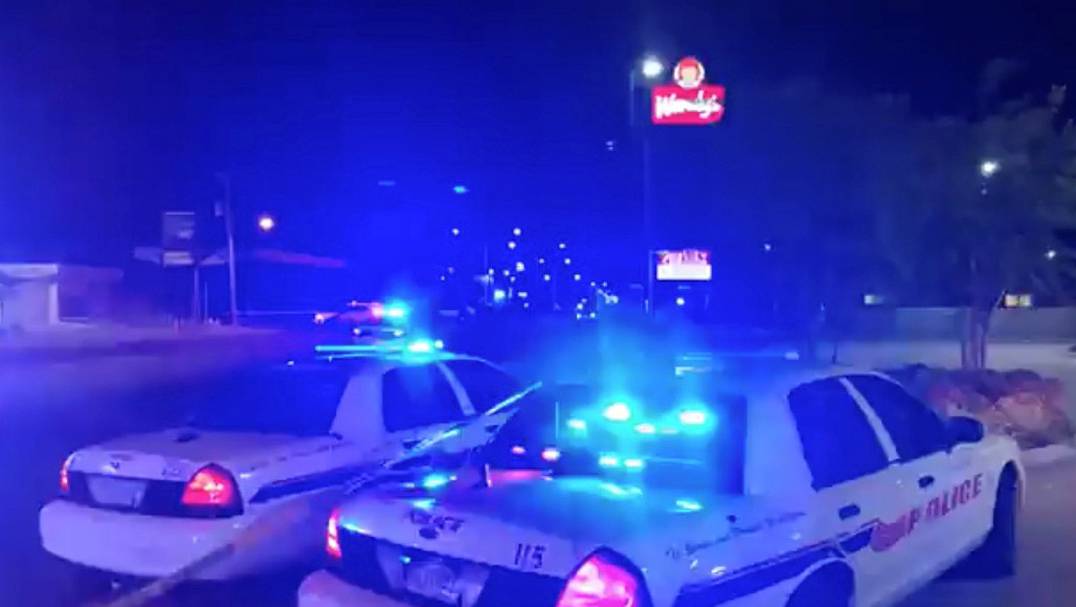 Police vehicles are seen near the scene in the aftermath of a drive-by shooting at a liquor store in Shreveport, Louisiana