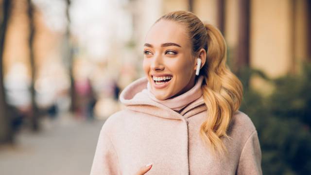 Stylish woman listening music on her airpods in city