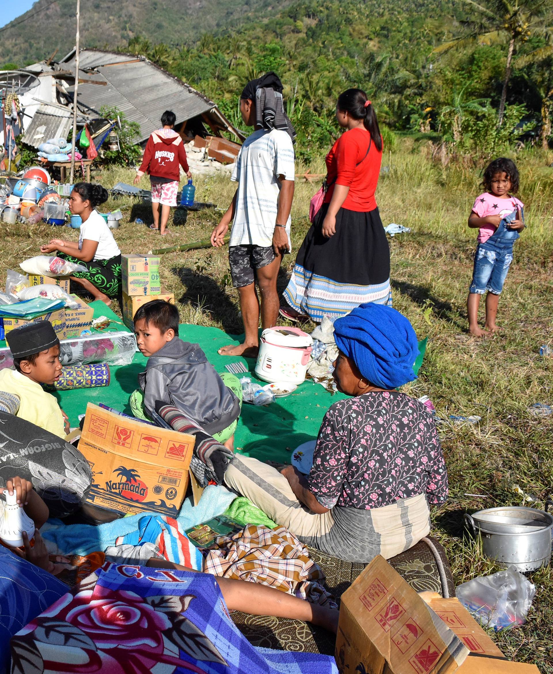 Residents sit outside their home with their belongings following a strong earthquake in Pemenang, North Lombok