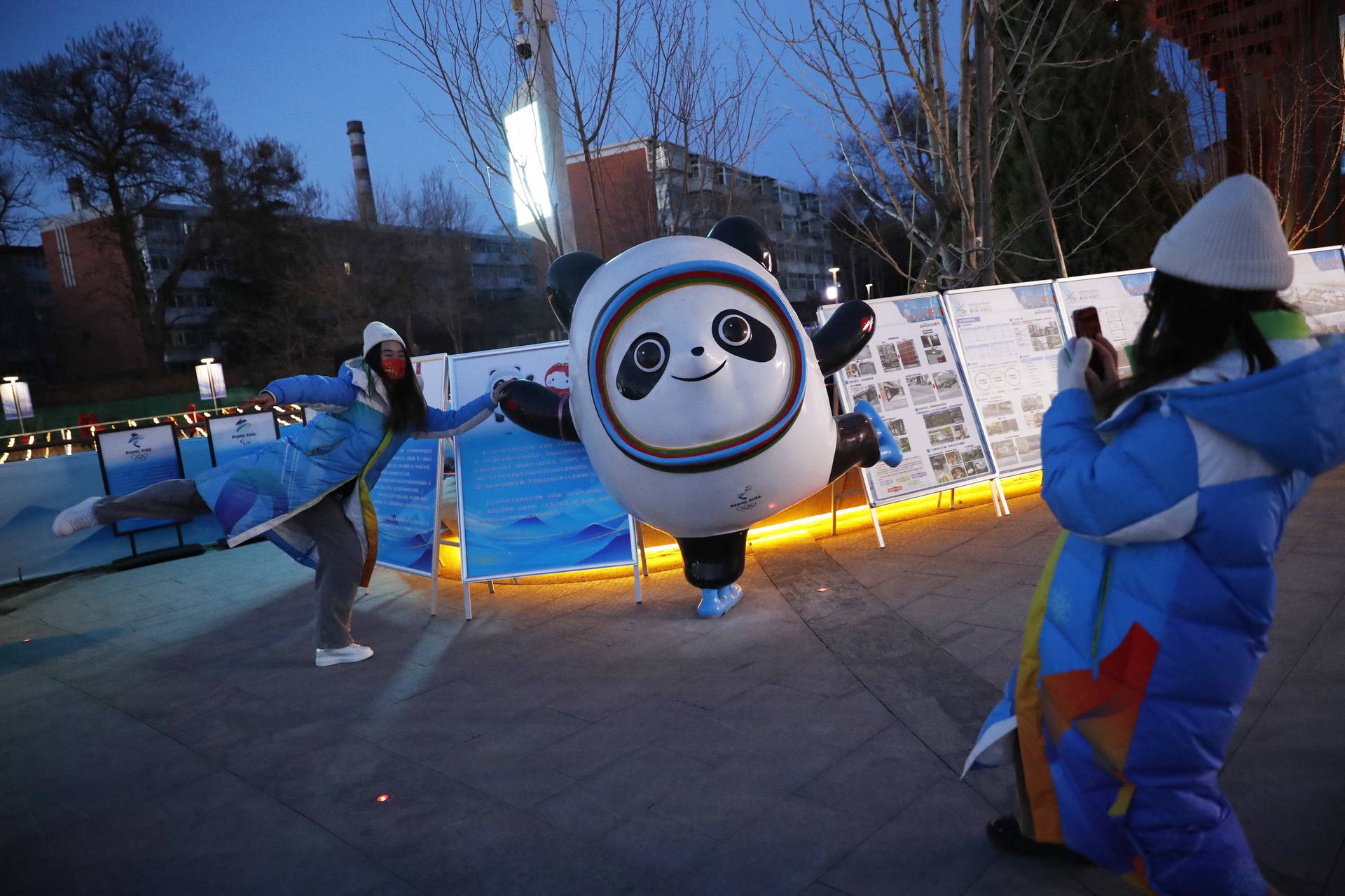 Volunteer poses for pictures with Bing Dwen Dwen at a community event in Beijing