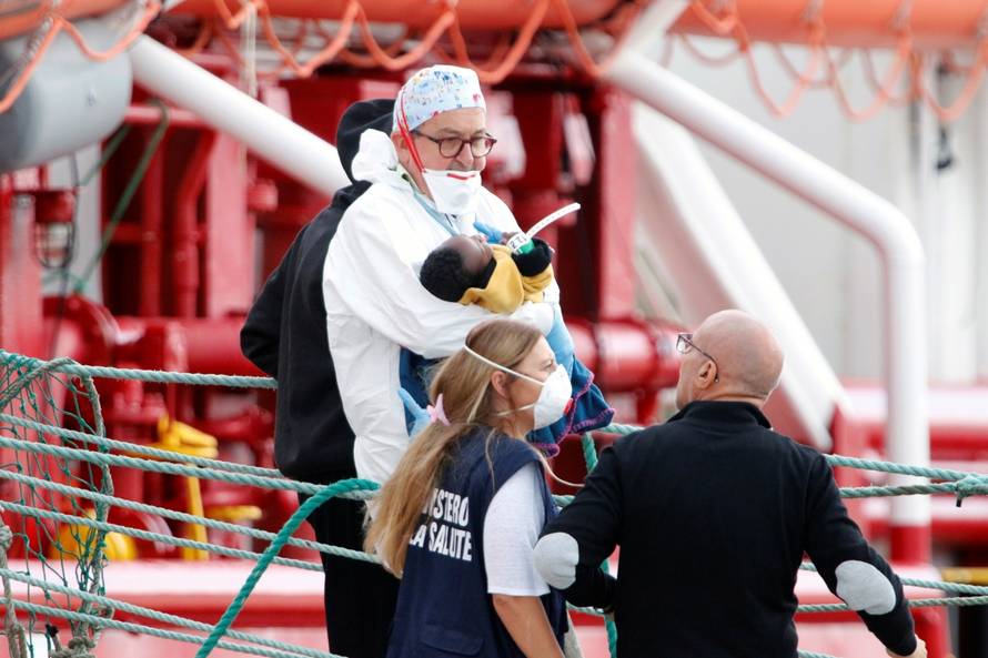 An Italian doctor at the Pozzallo port, Vincenzo Morello carries a child as migrants disembark at the port after spending nearly two weeks on board the Medecins Sans Frontieres (MSF)-operated Ocean Viking