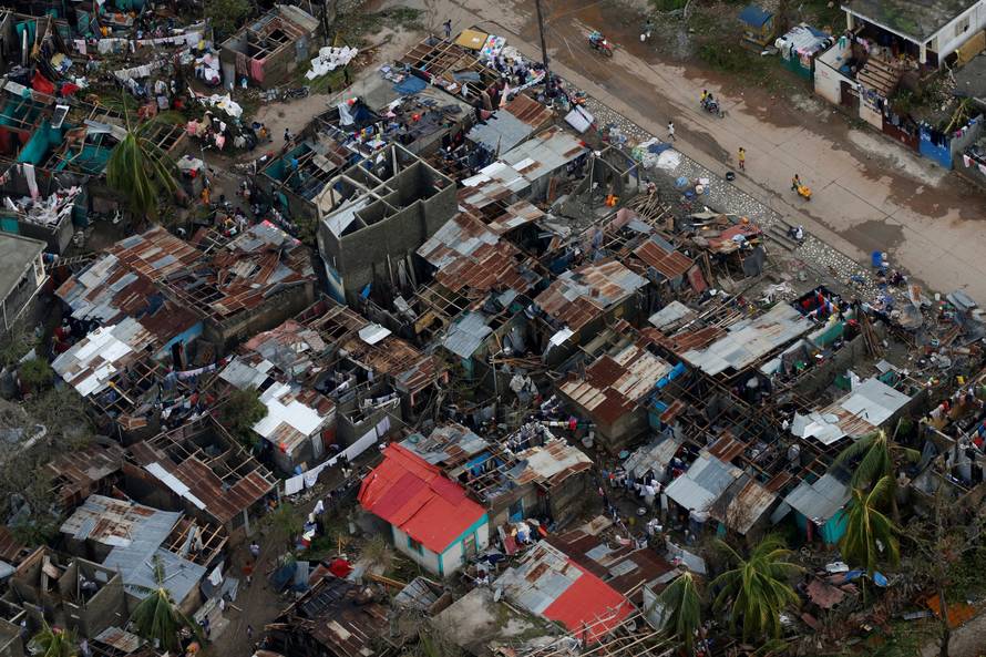 People walk down the street next to destroyed houses after Hurricane Matthew passes Jeremie, Haiti