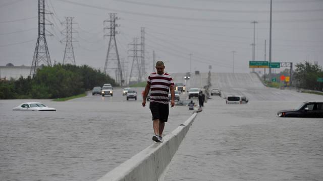 A stranded motorist escapes floodwaters on Interstate 225 after Hurricane Harvey inundated the Texas Gulf coast with rain causing mass flooding