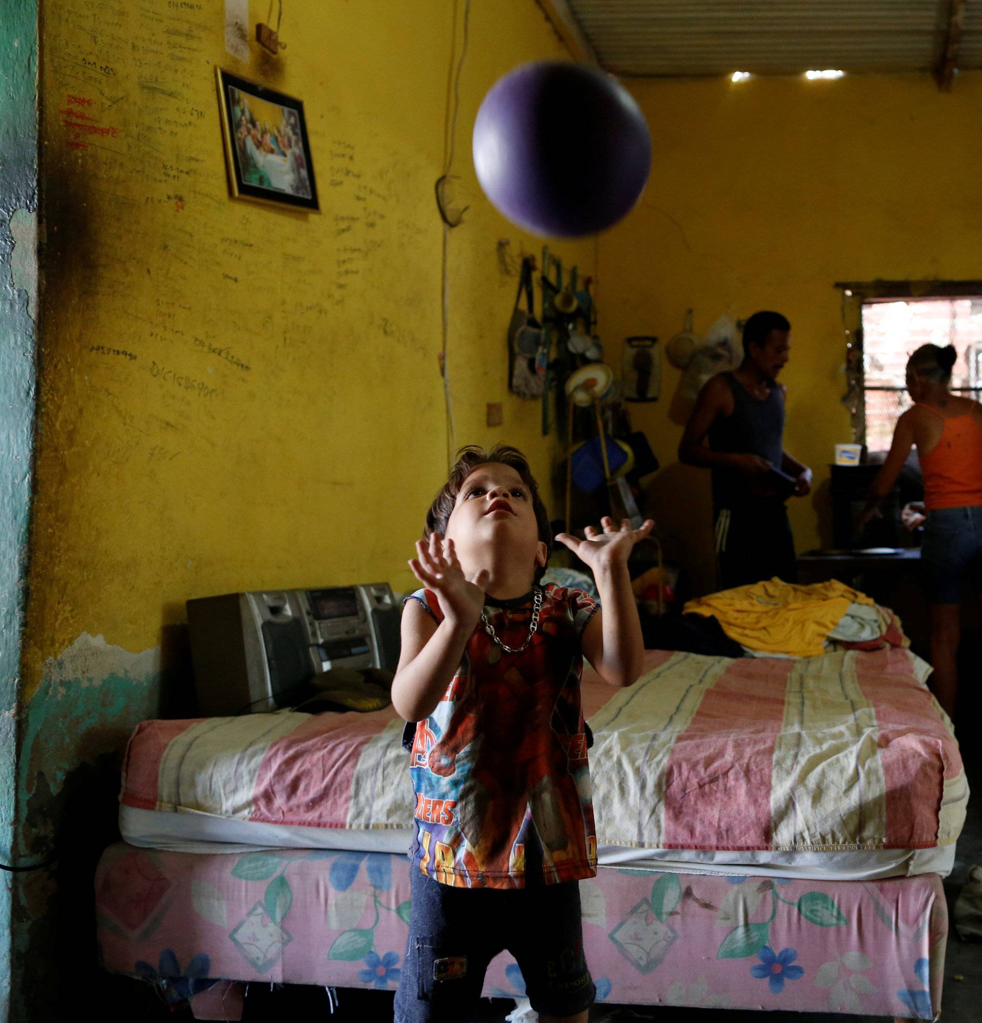 Emmanuel Cuauro plays with a ball next to his parents Zulay Pulgar and Maikel Cuauro in their house in Punto Fijo