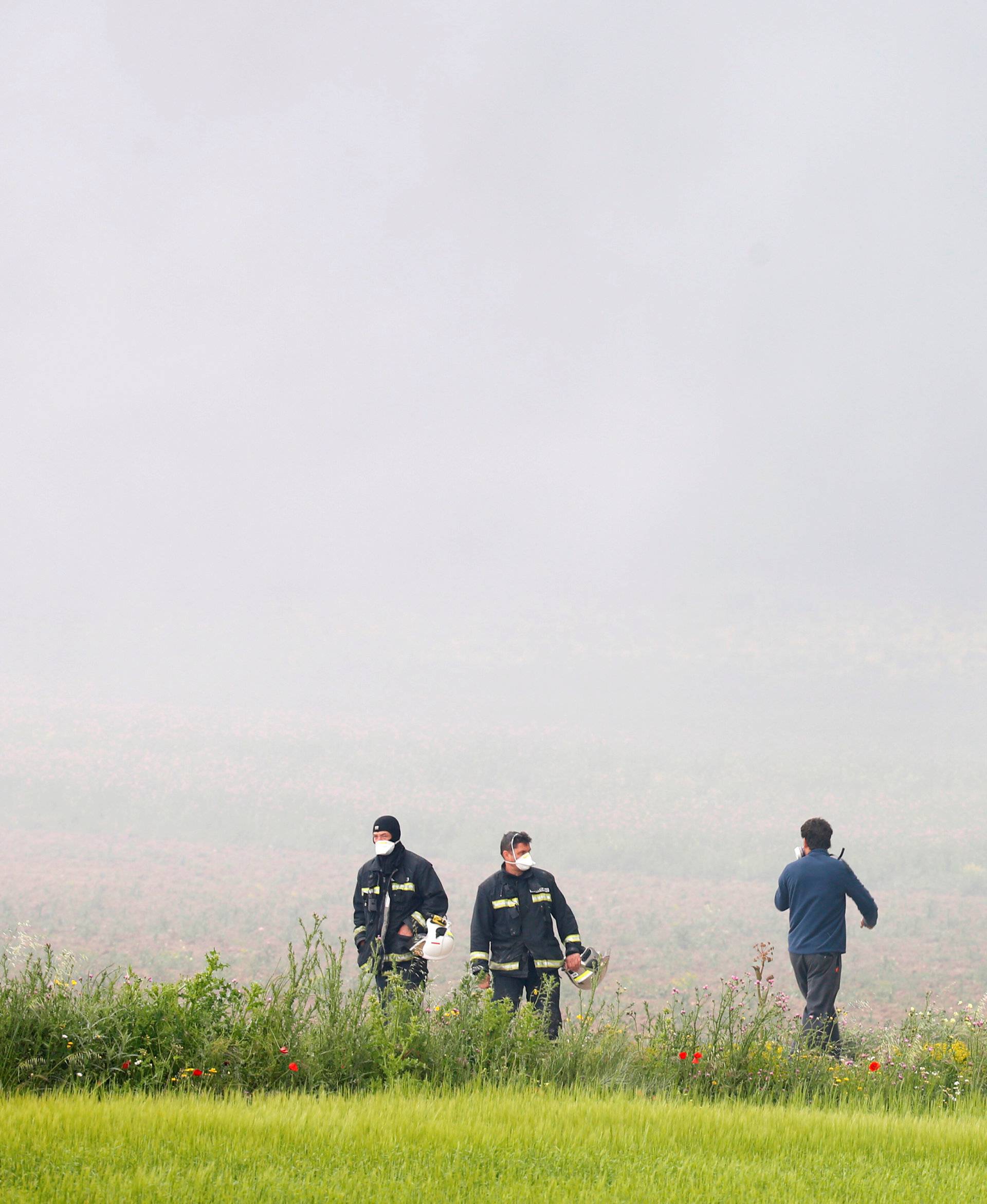 Firefigthers walk amidst smoke during a fire at a tire dump near a residential development in Sesena