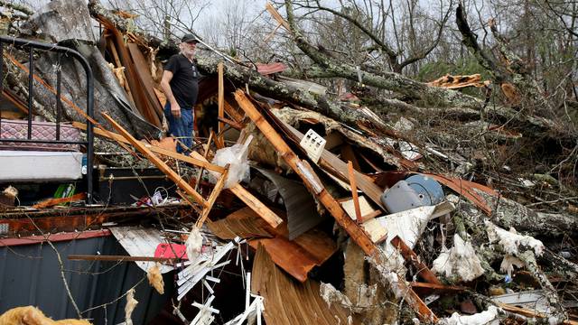 Larry Fondren sorts through the rubble of his mobile home destroyed by a tornado in Alabama