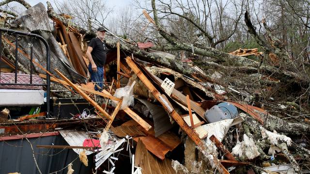 Larry Fondren sorts through the rubble of his mobile home destroyed by a tornado in Alabama