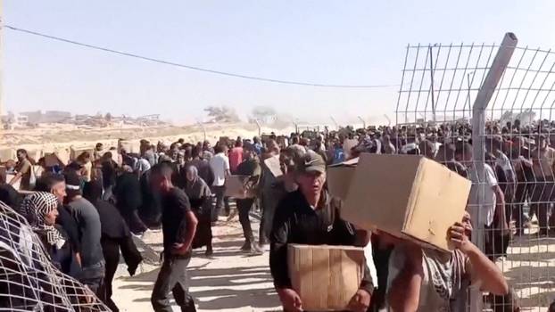 Palestinians walk back carrying aid boxes, in Rafah